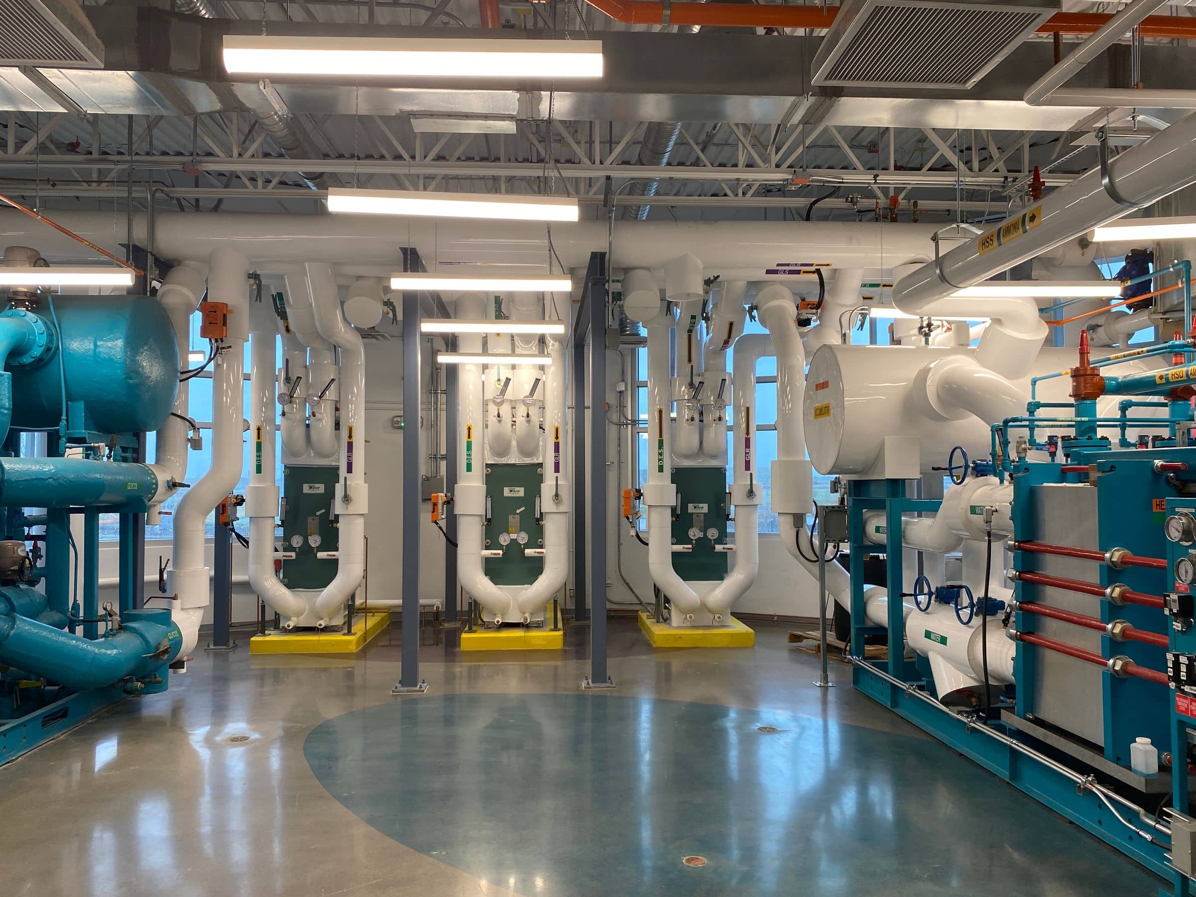 Complex commercial mechanical plant room with chillers, piping, and heat exchangers